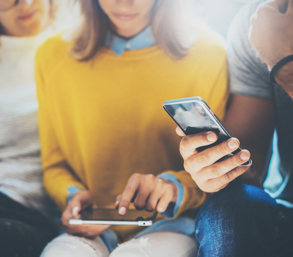 Team sitzt zusammen und schaut auf Smartphones